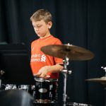 Montessori child playing drums in band.