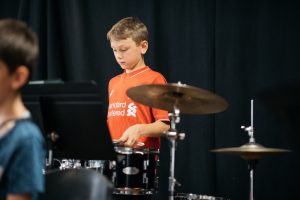 Montessori child playing drums in band.