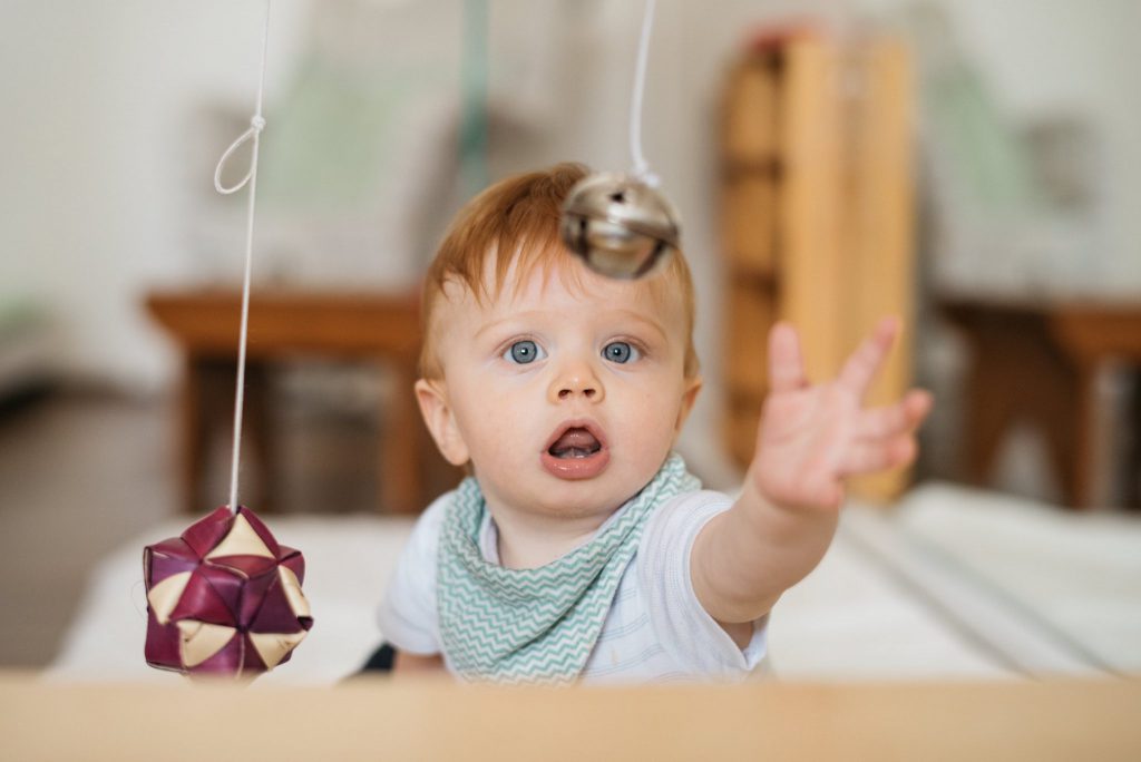 Infant grasping a hanging bell