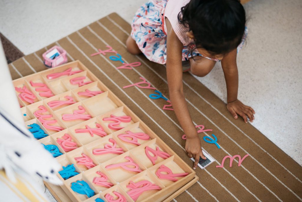 Child playing with moveable Montessori alphabet.