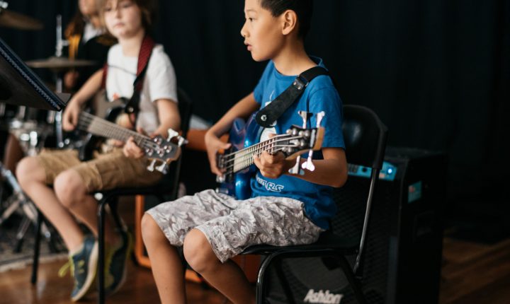 Children playing guitars in a band.